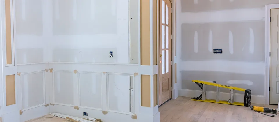 A room under renovation with new drywall and wainscoting panels.