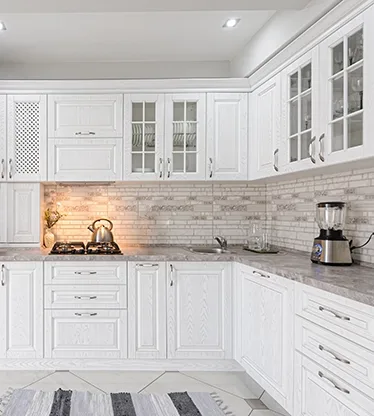 A white kitchen with new cabinets and a stone tile backsplash.